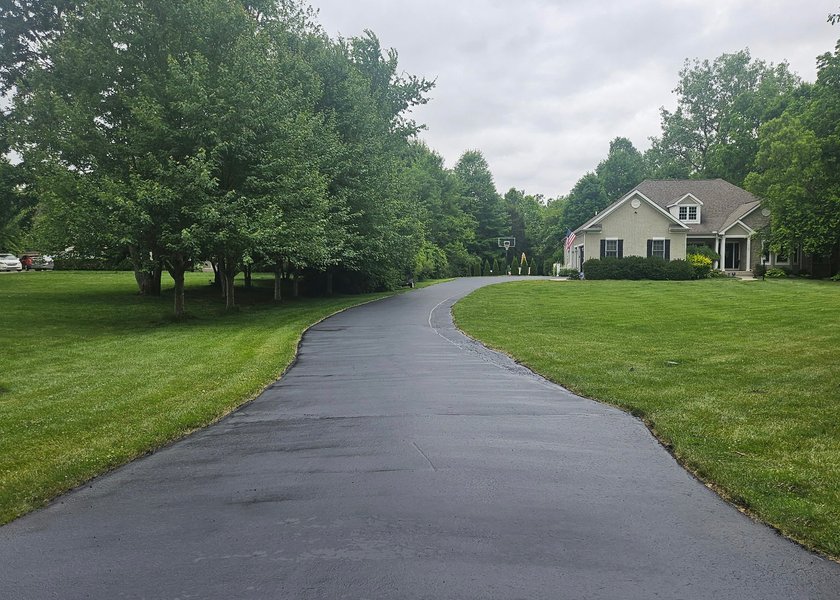 freshly sealed driveway pad beside a building