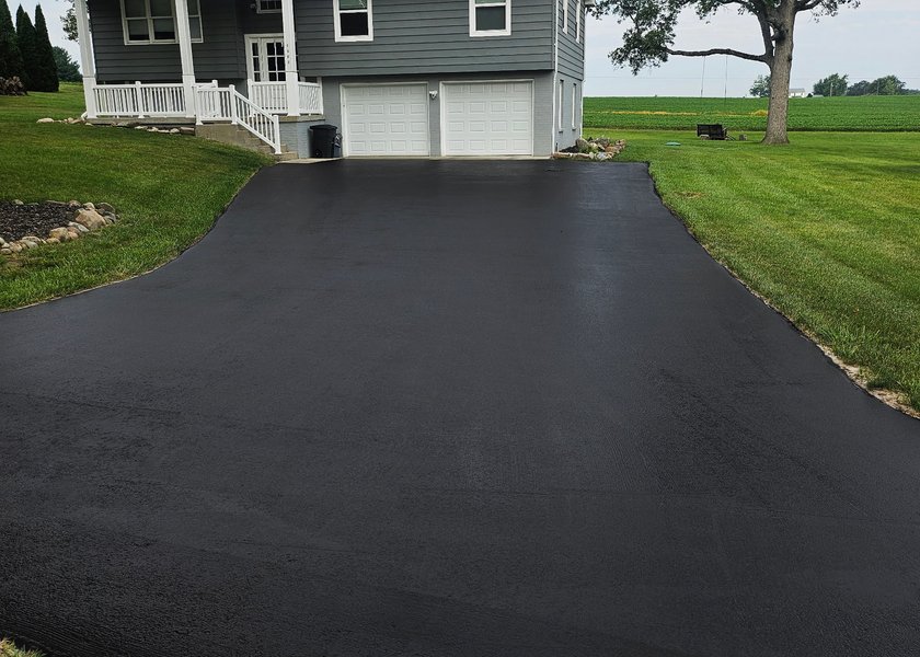 driveway surface with fresh asphalt sealer drying after service