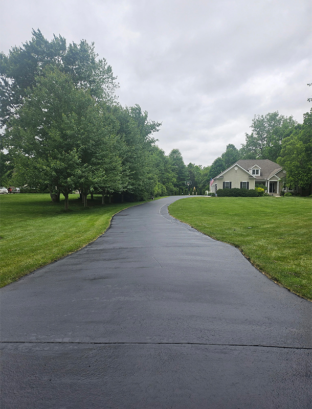 freshly sealed driveway pad beside a building